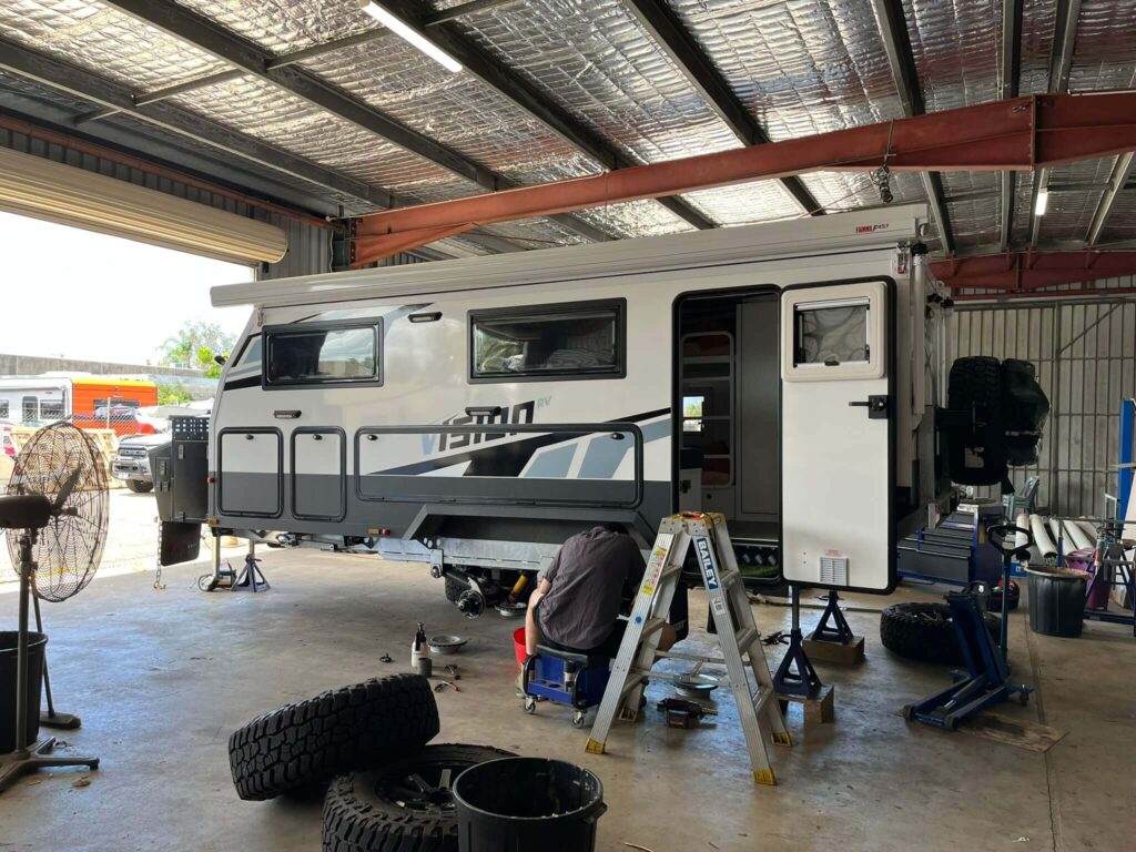 A close-up view of a caravan's wheel hub and undercarriage exposed for routine caravan service and repairs.