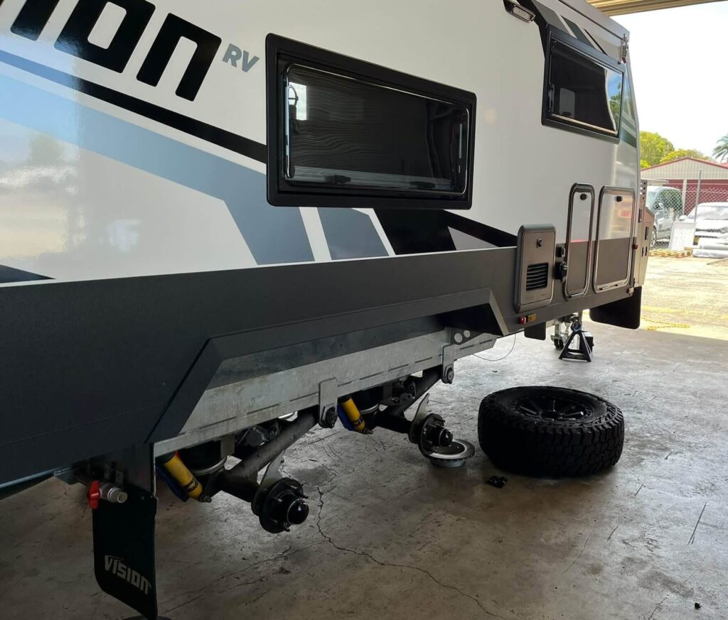 A modern caravan securely raised in our workshop for expert caravan service and repairs. The wheels are removed to perform detailed undercarriage and brake maintenance as part of our comprehensive caravan servicing.